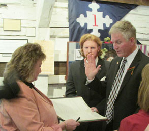 man hold up hand and read oath of office with woman holding a book