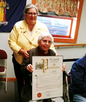 woman in wheelchair holds large plaque