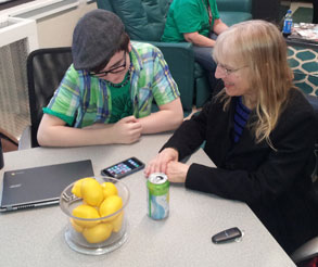 teen works on a smart phone with a senior citizen