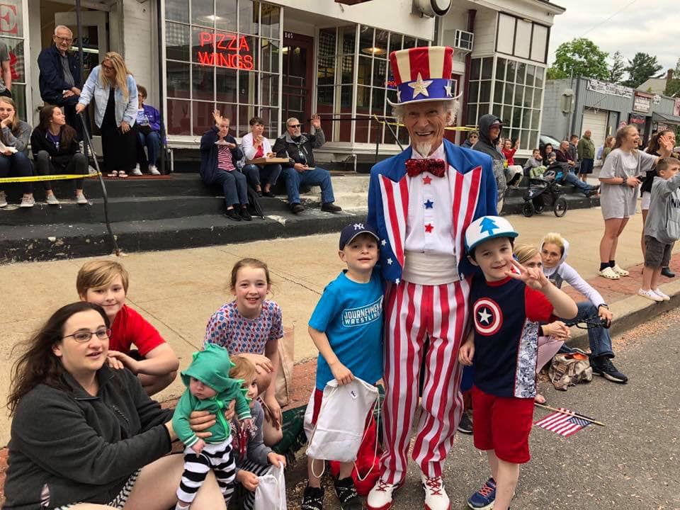 children sit with Uncle Sam waiting for parade