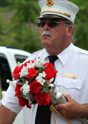 fireman marches in parade carrying flowers