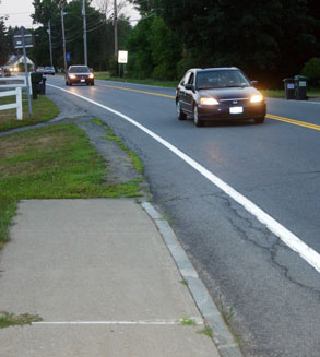 car drives down road with headlights on
