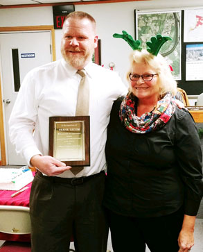 man holds up plaque with woman in reindeer ears next to him