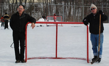 two men stand near hockey goal on the ice