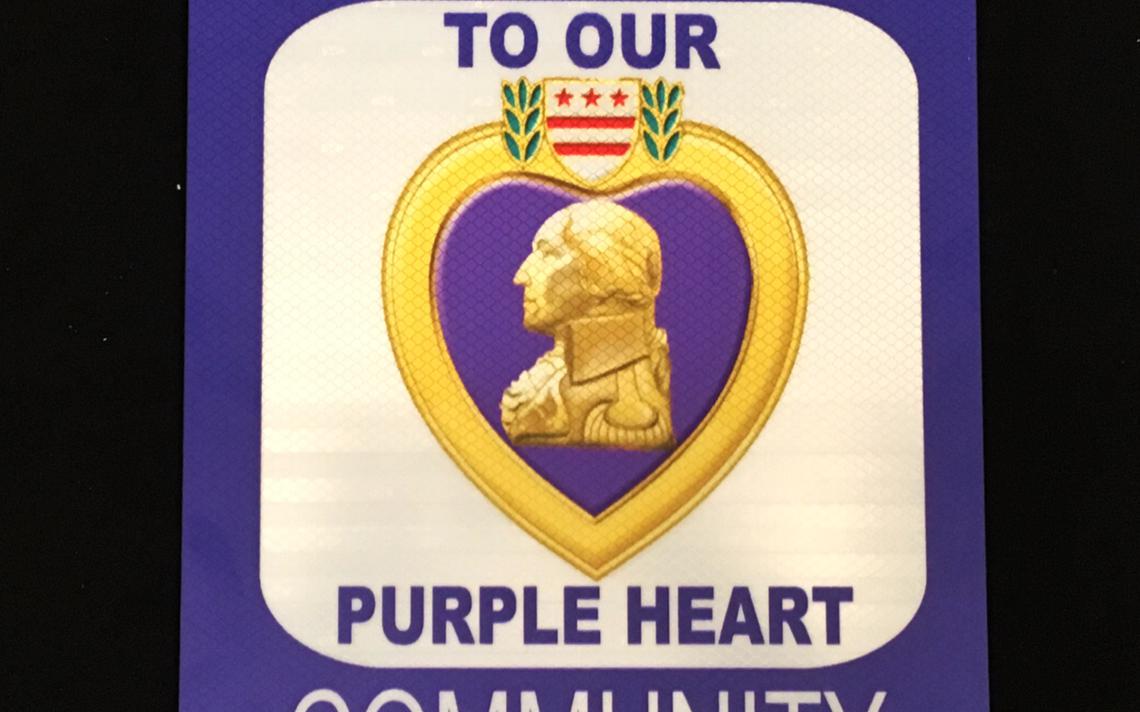 sign with a purple heart logo and the words To Our Purple Heart Community
