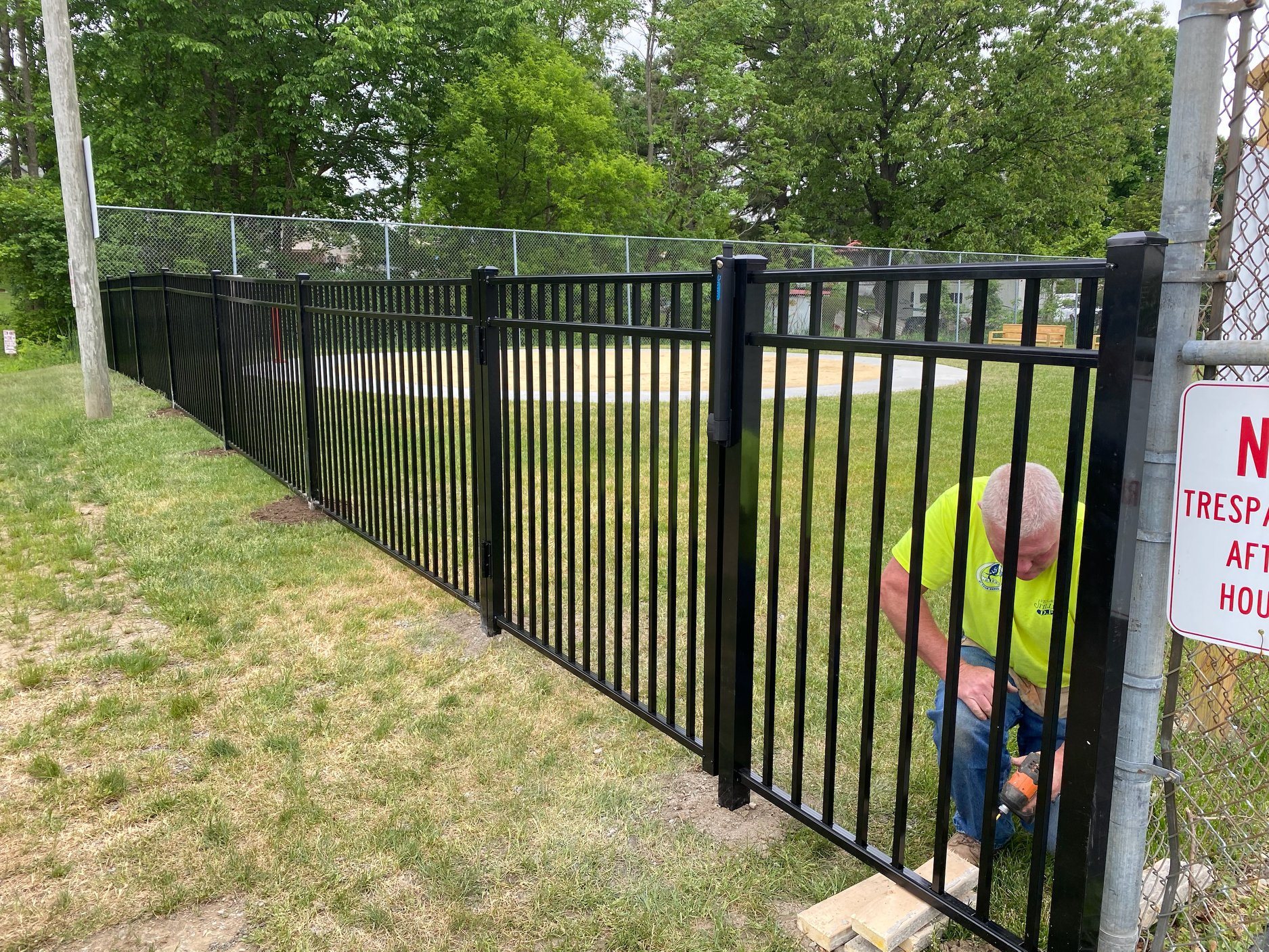 man installs a black fence
