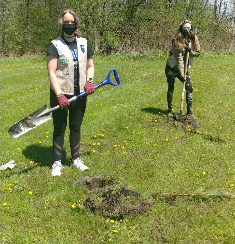 two girls scouts plant trees in a park