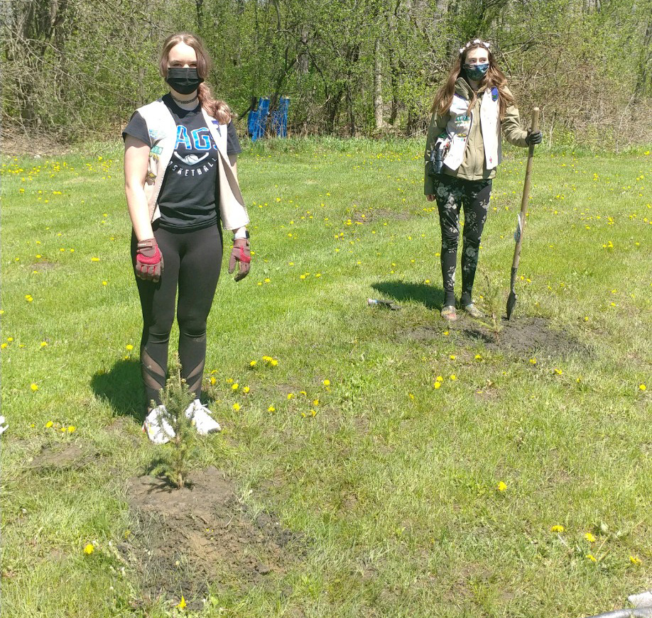 two girls scouts plant trees in a park