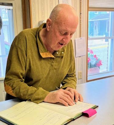 man signs a book for Trustee office