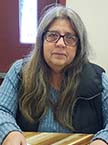 woman with long hair and glasses wearing a vest